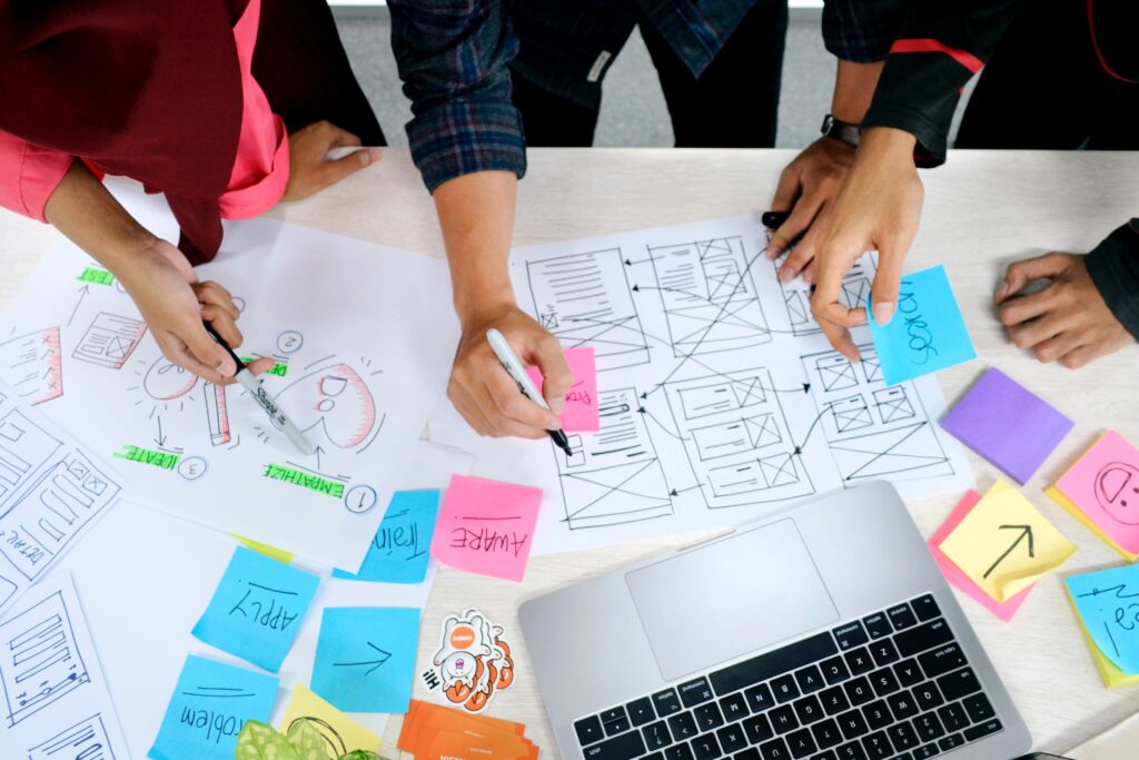 Équipe en atelier expérience client en co-création travaillant sur un parcours client avec des post-it et un ordinateur portable
